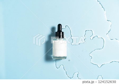 Hydrating serum on a calm blue background, enhanced by soft water droplets. 124152630
