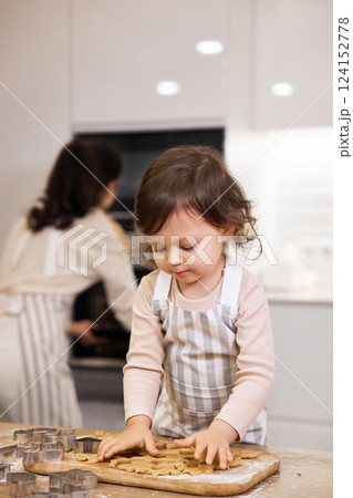 Cute little child girl in apron helping mom bake cookies in the kitchen Cute little child girl in apron helping mom bake cookies in the kitchen 124152778