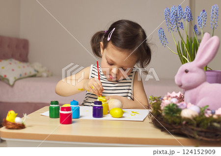 Little child girl paint Easter eggs at home. kid is preparing for Easter. 124152909