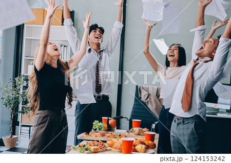 Asian office colleagues and friends enjoy a daytime BBQ with pizza and beer, celebrating Halloween and cheering for their favorite soccer team, creating a lively atmosphere filled with joy. 124153242