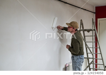 Painter in dirty clothes renovate a wall in a loft Painter in dirty clothes renovate a wall in a loft 124154050