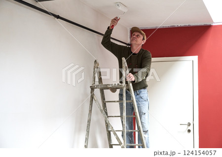 Painter in dirty clothes renovate a wall in a loft 124154057