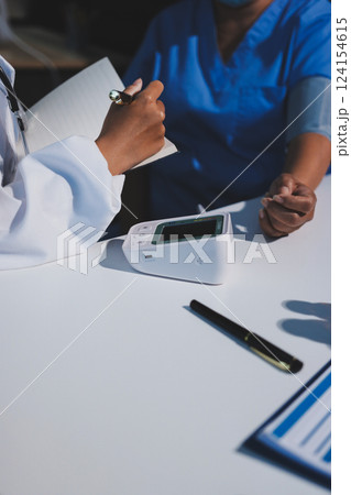 Doctor using sphygmomanometer with stethoscope checking blood pressure to a patient in the hospital. 124154615