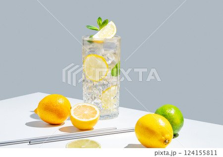 Lemonade with lemon, mint and ice in a glass on a white gray background with shadow and fruits. 124155811