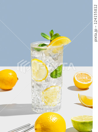 Drink with lemon, mint and ice in a glass on a white blue background with shadow and fruits. Drink with lemon, mint and ice in a glass on a white blue background with shadow and fruits. 124155812