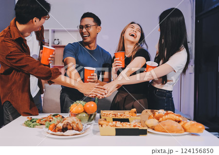 Happy young friends group having lunch at home. Asia family party eating pizza food and laughing enjoying meal while sitting at dining table together at house. Celebration holiday and togetherness. 124156850