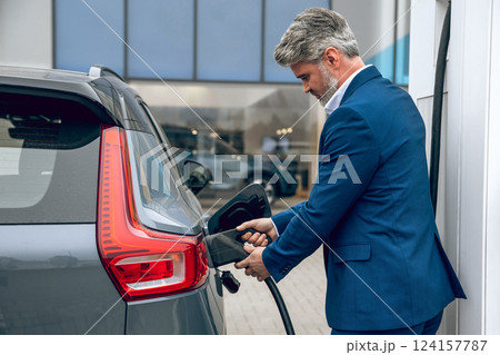 Man wearing official style suit at pump fueling his automobile with diesel 124157787