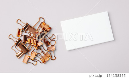 Heap of copper gold binder clips and memo note paper on light grey background 124158355