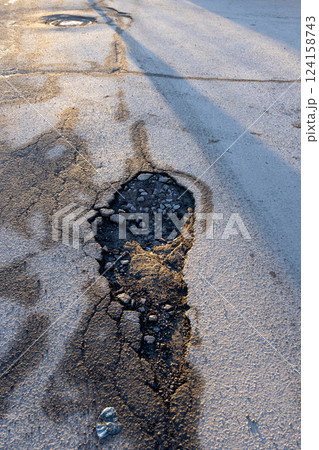 potholes in the road, holes in the asphalt on the roadway or highway. potholes in the road, holes in the asphalt on the roadway or highway. 124158743