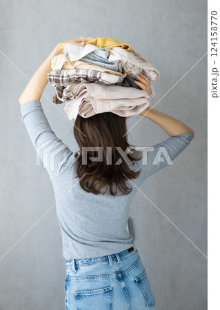 washing clothes, back view woman holds stack of clothes on head after dry cleaning. washing clothes, back view woman holds stack of clothes on head after dry cleaning. 124158770