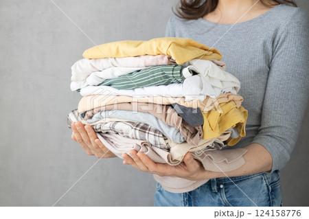 Laundry, woman holds stack of clothes in her hands after dry cleaning. housework, cleaning ironing. Laundry, woman holds stack of clothes in her hands after dry cleaning. housework, cleaning ironing. 124158776