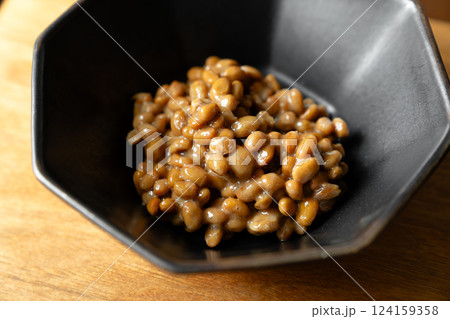 ネバネバの糸を引いている納豆　黒いボウル　木製テーブルの背景 124159358
