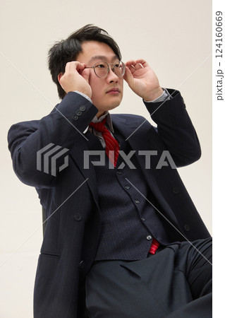 Side view portrait of young handsome Asian man dressed formal attire, looking serious and focused, adjusting his eyeglasses against white background. Side view portrait of young handsome Asian man dressed formal attire, looking serious and focused, adjusting his eyeglasses against white background. 124160669