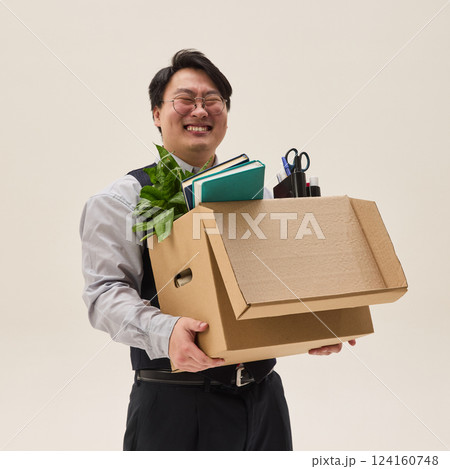 Young guy, Asian, carries large box of his belongings, moving to new office against large background. Man happy to get new job. Young guy, Asian, carries large box of his belongings, moving to new office against large background. Man happy to get new job. 124160748