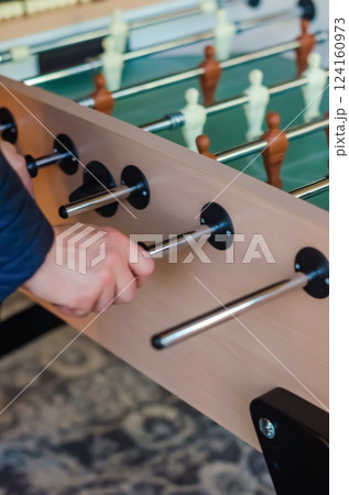 Close-up of a hand playing foosball, gripping the handle during a game match. High quality photo 124160973