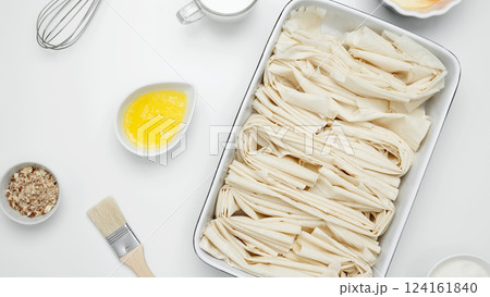 Filo dough in a baking dish next to Crinkle Cake butter for greasing Filo dough in a baking dish next to Crinkle Cake butter for greasing 124161840
