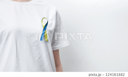 Symbolizing World Down Syndrome Day. A person wearing a white t-shirt with a yellow and blue awareness ribbon 124161882