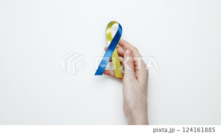 Symbolizing World Down Syndrome Day. A person holds a yellow and blue awareness ribbon Symbolizing World Down Syndrome Day. A person holds a yellow and blue awareness ribbon 124161885
