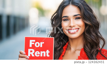 Smiling woman holding a red For Rent sign outdoors, promoting real estate, housing opportunities, and property rentals. 124162431
