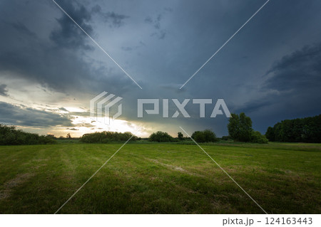 A dark rain cloud over a green meadow A dark rain cloud over a green meadow 124163443