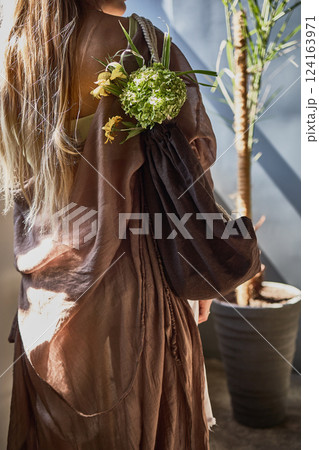 Elegant woman with floral bouquet, draped in brown, sunlight streaming in, elegant fashion statement, natural styling concept Elegant woman with floral bouquet, draped in brown, sunlight streaming in, elegant fashion statement, natural styling concept 124163971