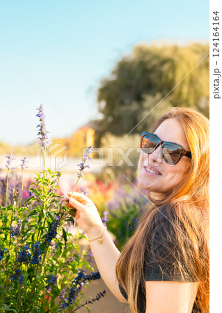 Young woman enjoying scent in blooming spring garden. The concept of youth, love, fashion and lifestyle. 124164164