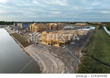 Development of residential housing in American suburbs. Unfinished frames of apartment condos with wooden roof beams under construction. Real estate market in the USA Development of residential housing in American suburbs. Unfinished frames of apartment condos with wooden roof beams under construction. Real estate market in the USA 124164486