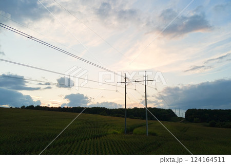 Dark silhouette of high voltage tower with electric power lines at sunrise. 124164511