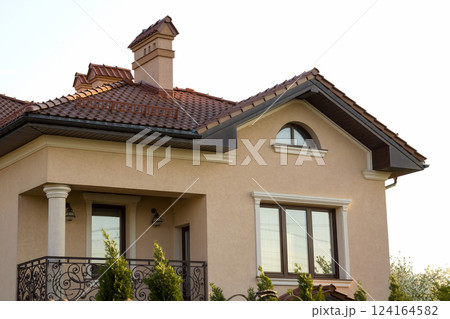 Close up of spacious brown shingle roof of modern luxurious expensive residential cottage house with three chimneys, big windows and gutters pipes. Construction, sale, buying and mortgage concept. Close up of spacious brown shingle roof of modern luxurious expensive residential cottage house with three chimneys, big windows and gutters pipes. Construction, sale, buying and mortgage concept. 124164582