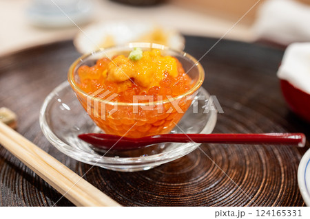 Japanese appetizer of salmon roe served in a glass bowl topped with sea urchin and wasabi 124165331