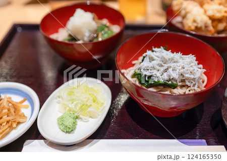 Bowl of cold soba noodles with fresh shirasu fish, accompanied by condiments like wasabi, scallions 124165350