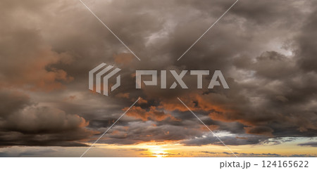 Bright sunset with setting sun behind vivid orange and yellow clouds 124165622