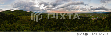Aerial wide panoramic view of dark mountain hills covered with green mixed pine and lush forest in evening. 124165703