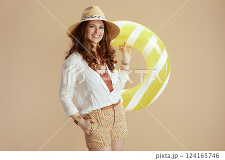 smiling trendy housewife in blouse and shorts on beige 124165746