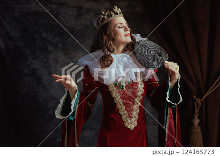 medieval queen in red dress with fan, white collar and crown 124165773