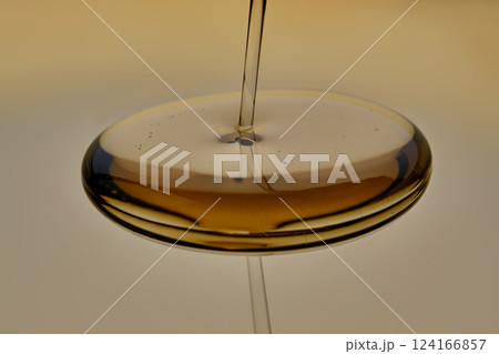 Texture of pouring cosmetic oil on a golden background. Texture of pouring cosmetic oil on a golden background. 124166857