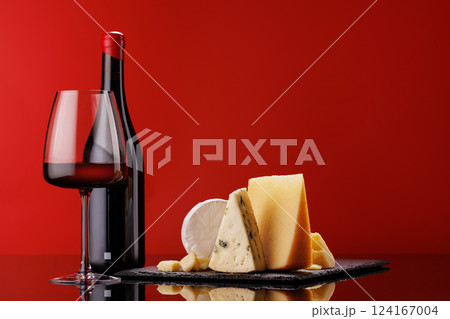 A refined selection of aged cheeses presented on a board, accompanied by a glass of wine 124167004