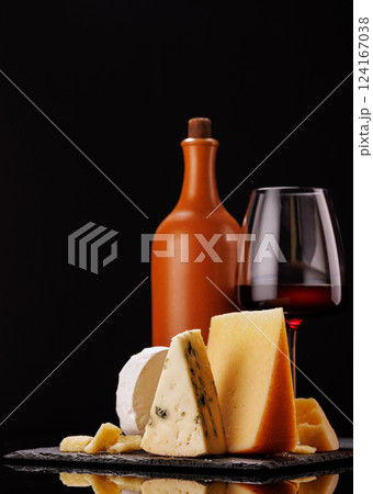 A refined selection of aged cheeses presented on a board, accompanied by a glasses of wine 124167038