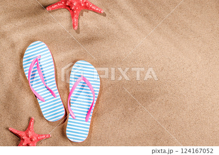 A tropical summer background featuring beach sand with palm leaf shadows and a pair of flip-flops 124167052