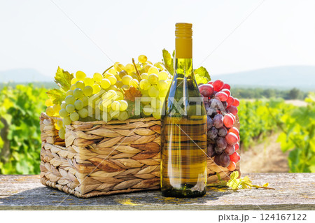 A basket filled with various types of grapes and bottle of white wine A basket filled with various types of grapes and bottle of white wine 124167122