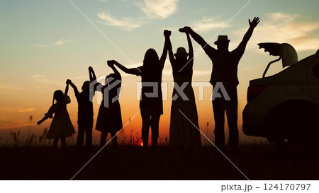 Happy family, silhouettes at sunset. Big family kids childs siblings parents holding hands appreciating enjoying orange setting sun together by car. Closeness family bonds joint recreation at nature 124170797