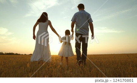 Cute family having fun at sunset, holding hands. Together mom mother daughter kid child dad father walk along field enjoying company weather. Parent girl at nature park. Hope happiness joyful concept 124170801