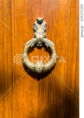 Closed wooden vintage door with golden old knocker in hot summer time. Vignette look. Vintage background. Closed wooden vintage door with golden old knocker in hot summer time. Vignette look. Vintage background. 124171105