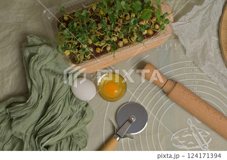 Rolling pin, cutter, eggs and microgreens sprouts on kitchen table worktop. Top view. Green towel. Homemade cooking baking puffs 124171394