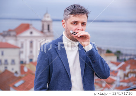 Man plays harmonica outdoors in city street Man plays harmonica outdoors in city street 124171710