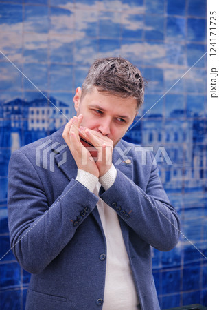 Man plays harmonica outdoors in city street 124171725
