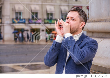 Man plays harmonica outdoors in city street Man plays harmonica outdoors in city street 124171726
