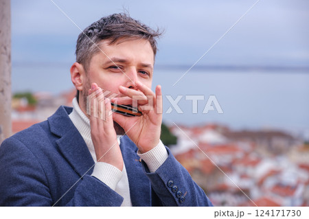 Man plays harmonica outdoors in city street Man plays harmonica outdoors in city street 124171730
