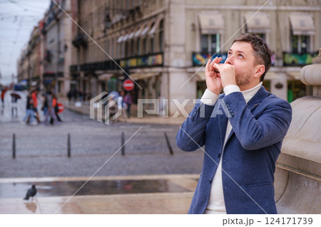 Man plays harmonica outdoors in city street 124171739