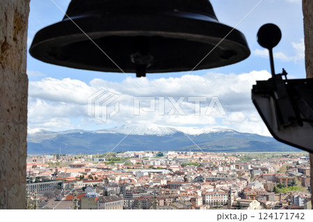 Front view bell atop Cathedral with village in background snow capped mountains 124171742
